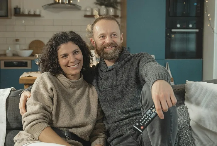A couple smiling watching TV together