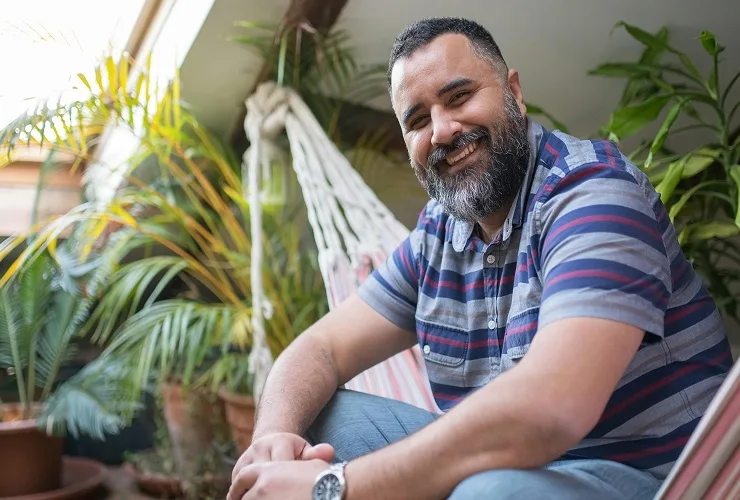 A man sitting on a hammock smiling to camera