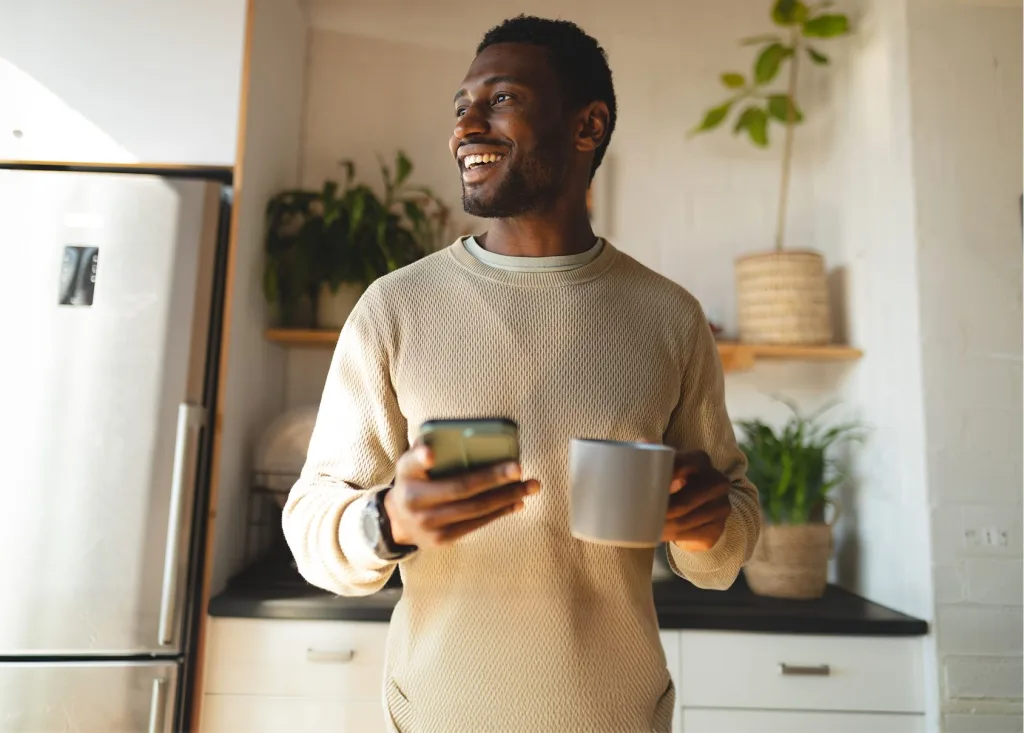 A man holding a cup while looking at his phone
