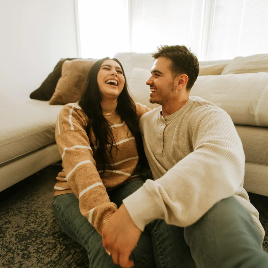 A happy couple sharing a laugh in their living room